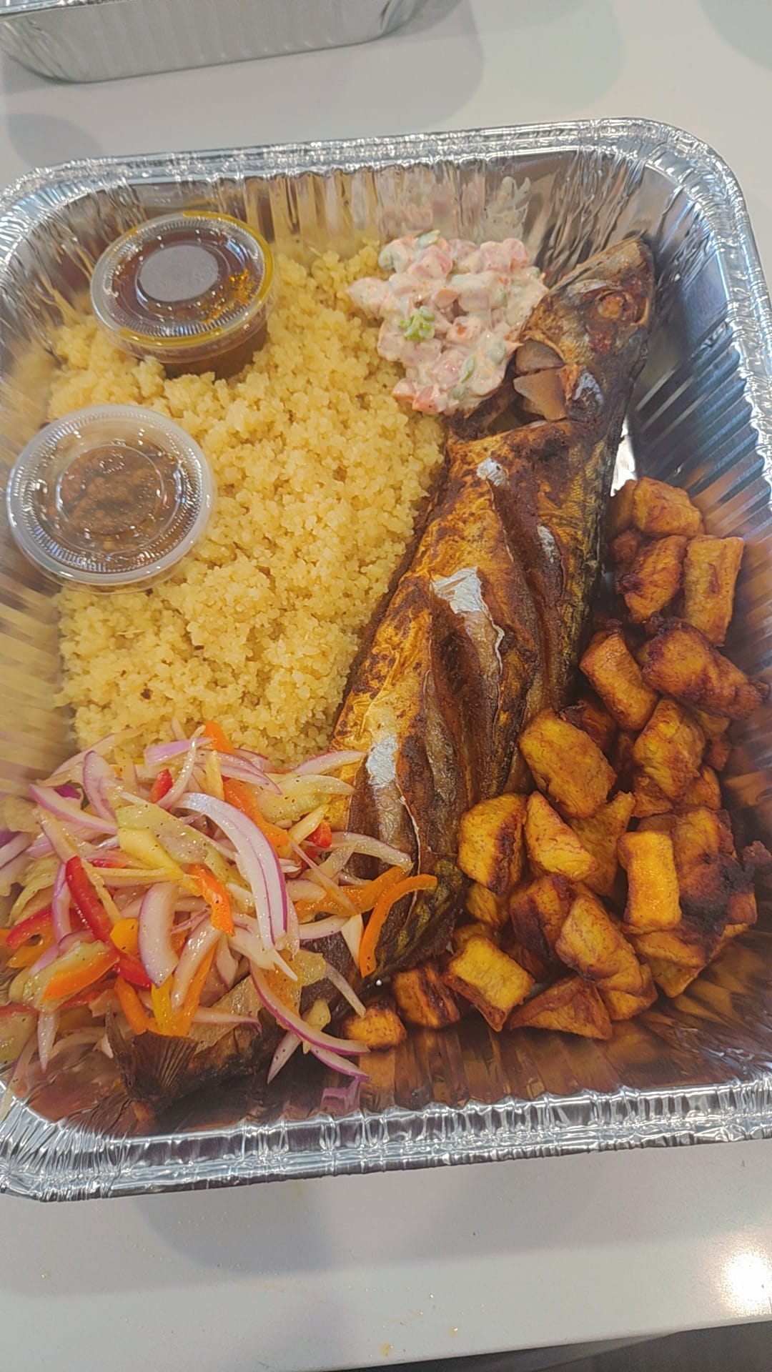 Attieke tray with whole fish, fried plantains and salad